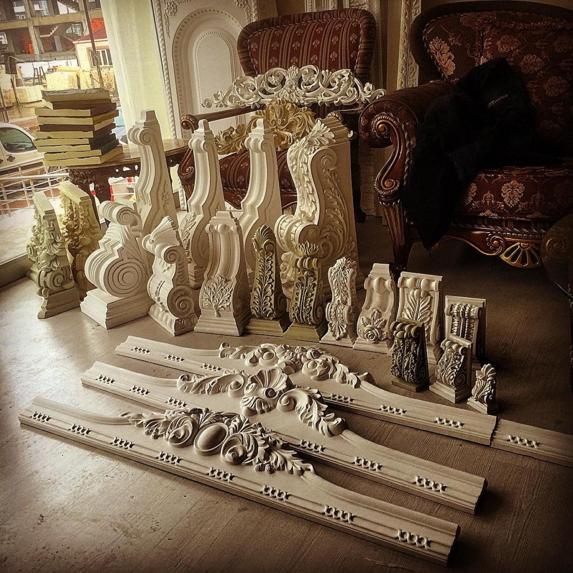 A collection of white polyurethane decorative corbels and architectural crown moldings showcased in a professional studio.