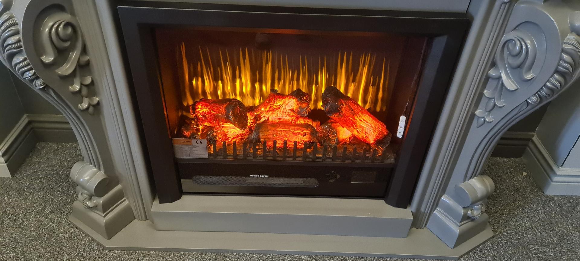 Cornice camino P8403W in poliuretano neoclassico in un soggiorno moderno grigio antracite con fiamme elettriche.