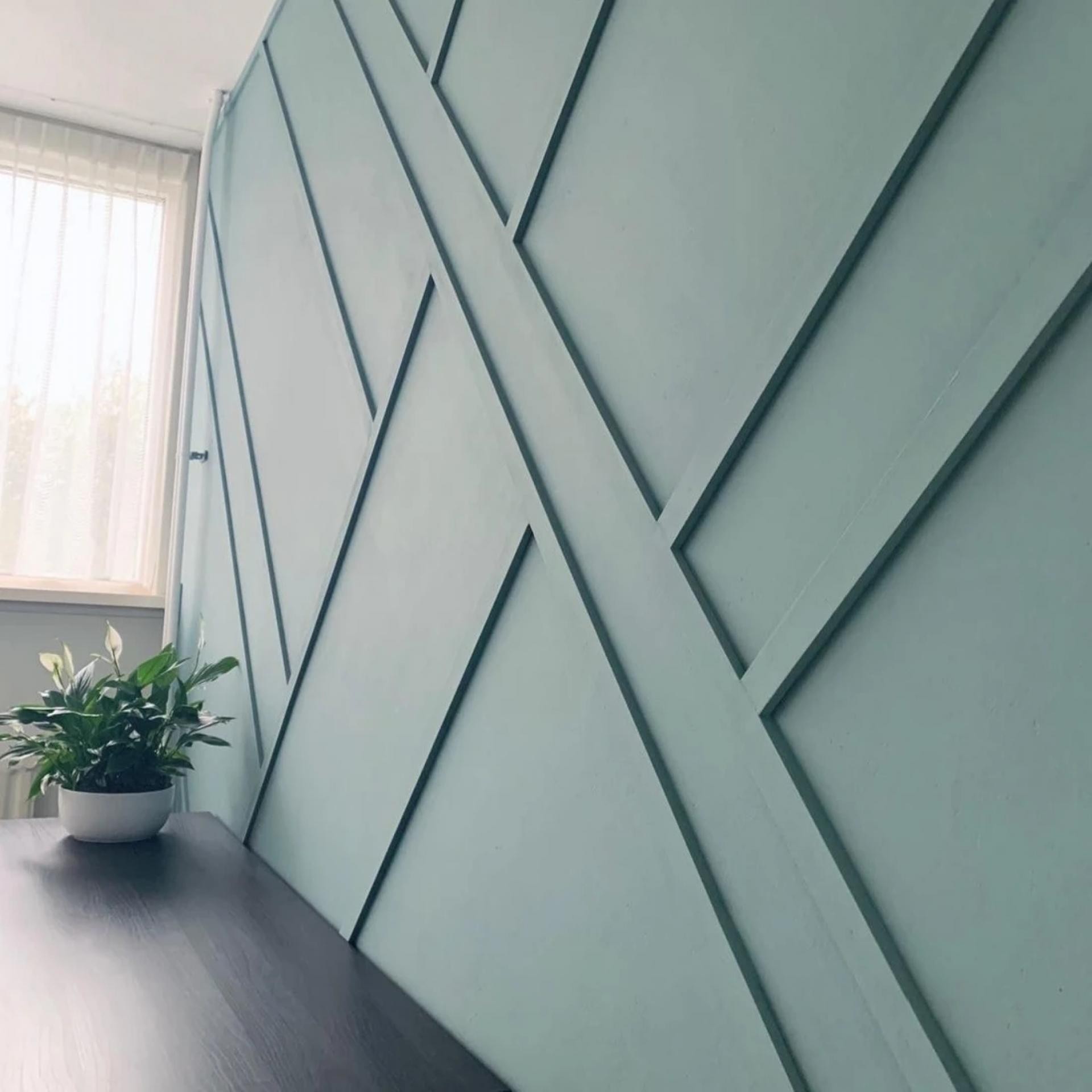 Interior design moderno con pareti verde salvia e cornici geometriche asimmetriche in poliuretano Polure.