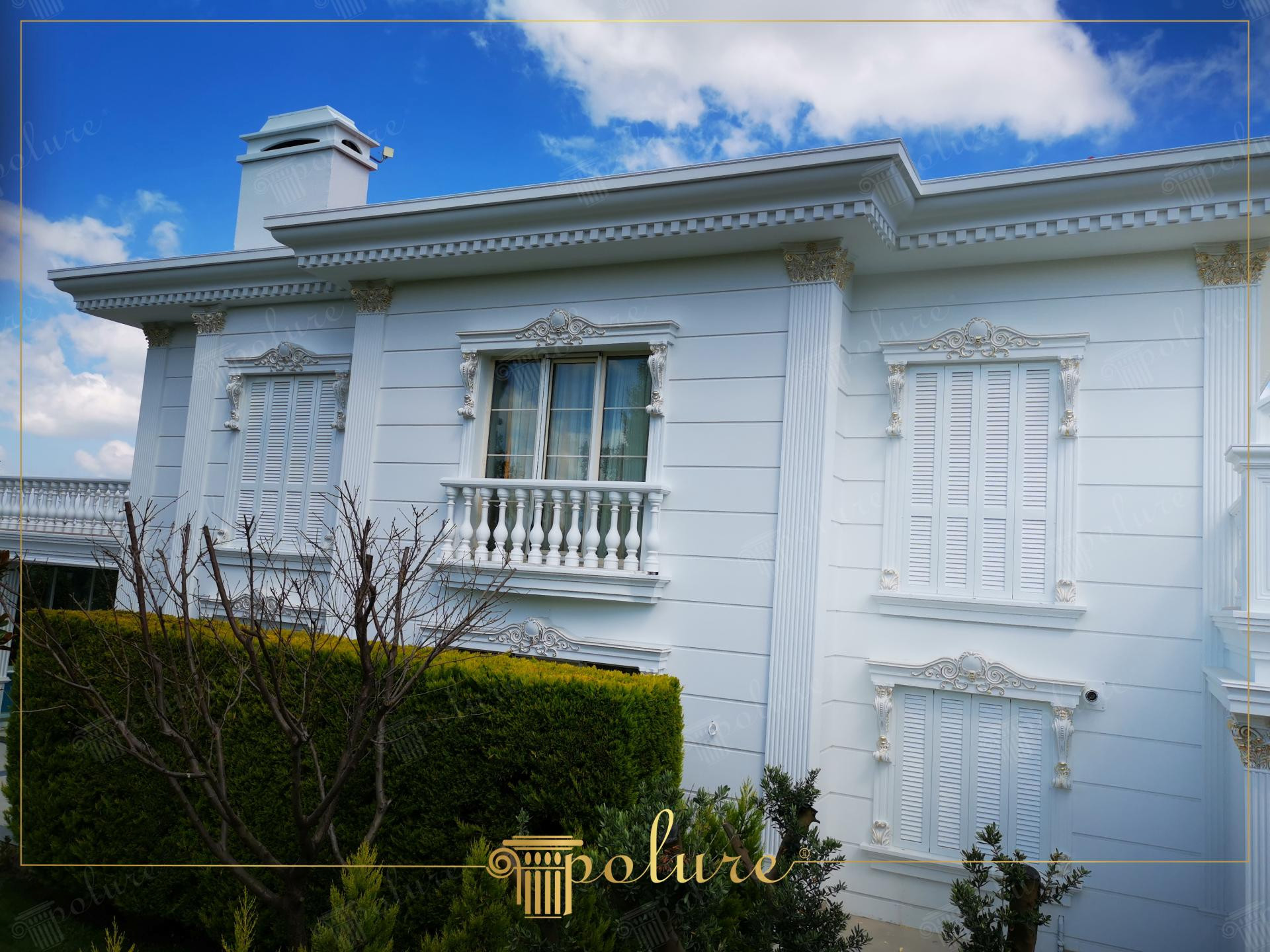 Esterno villa neoclassica con pilastri in poliuretano Polure, frontoni per finestre P2839 e pannelli decorativi bianchi.