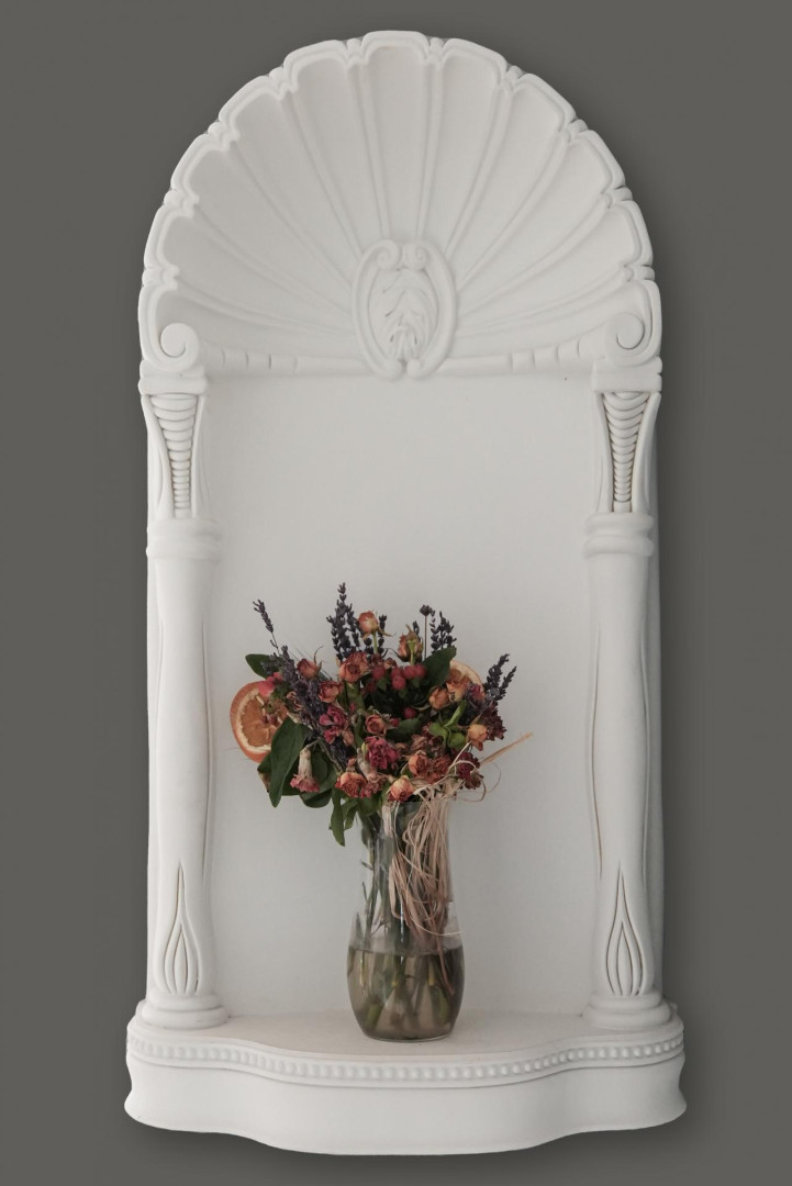 Nicchia decorativa Polure P09 in poliuretano bianco con motivo a conchiglia e colonne ioniche su parete scura.