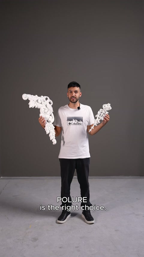 Lo studio mostra due elementi decorativi angolari lavorati con motivi fogliari tenuti in mano dal presentatore