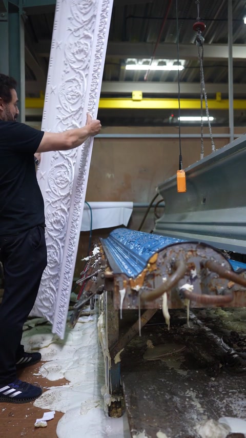 White ornate cornice profile held upright beside open mould line