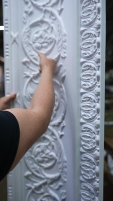 Fingertips trace deep undercut ornament on unfinished cornice surface