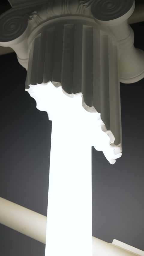 Intense white illumination visible at top of Ionic capital column