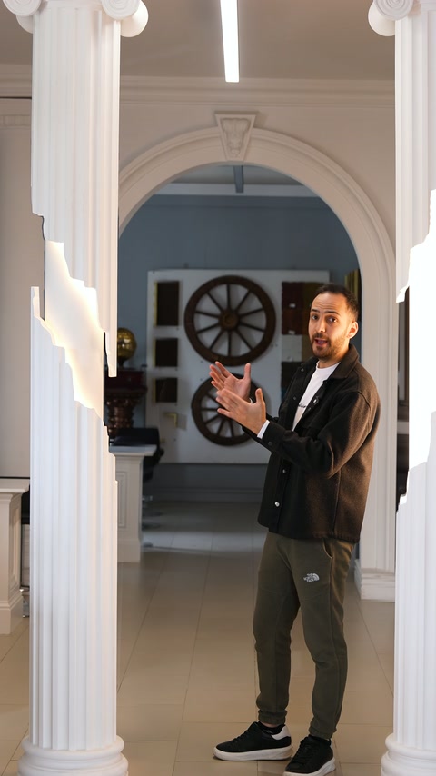 Presenter explains illuminated columns from side in arched showroom passage