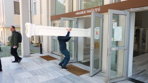 Görevliler üniversite girişinde etkinlik malzemelerini içeri taşıyor