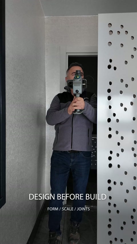 Tarama görevlisi dekoratif delikli panelin yanında cihazı yönlendiriyor