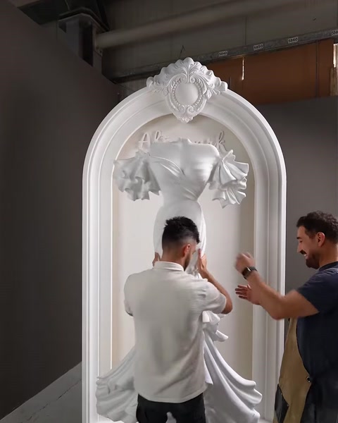 Workers mount the sculpted dress relief piece onto the arch panel.