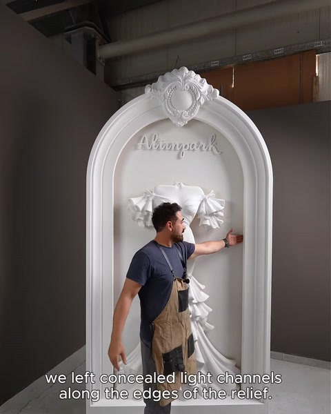 Craftsman beside finished arch explaining hidden LED light channels behind relief.