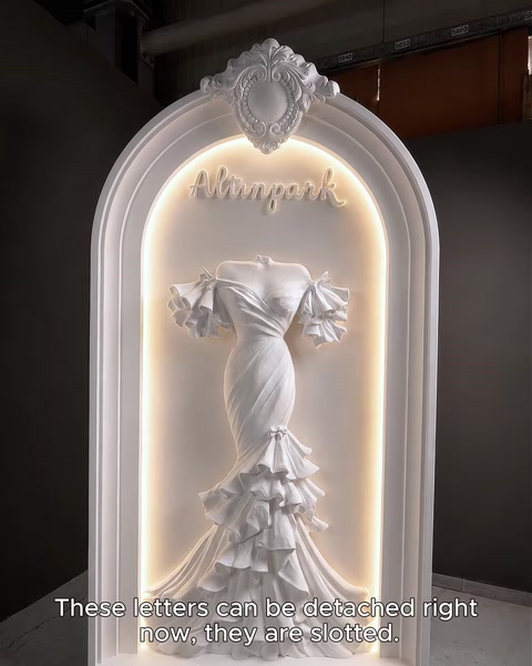 Illuminated arch with glowing boutique name and lit dress relief backlight.