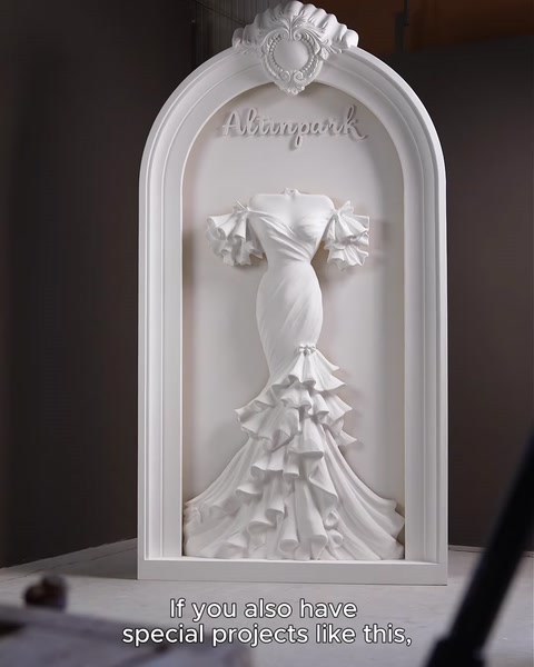 Freestanding matt-white polyurethane arch with wedding-dress relief, unlit, studio view.