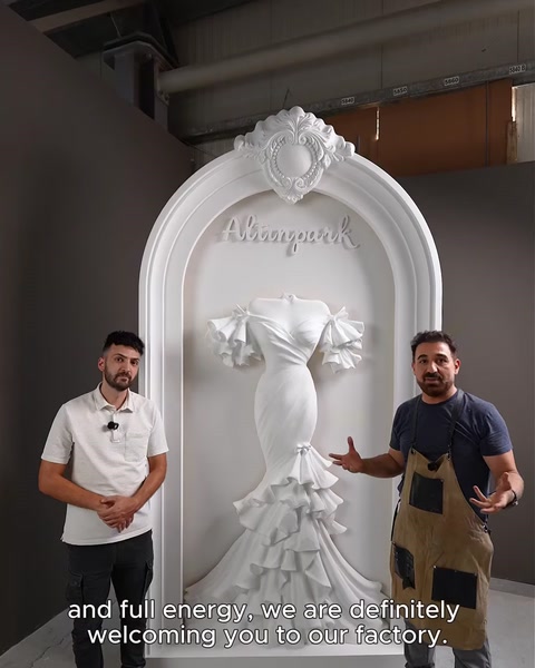 Two craftsmen standing beside the finished custom arch in the factory.