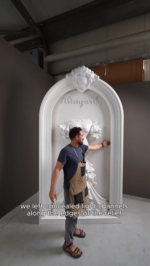 Artigiano accanto all'arco finito spiega i canali di illuminazione LED nascosti dietro il rilievo.