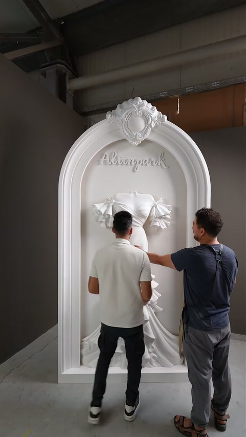 Two workers align the bodice relief against the recessed display panel.