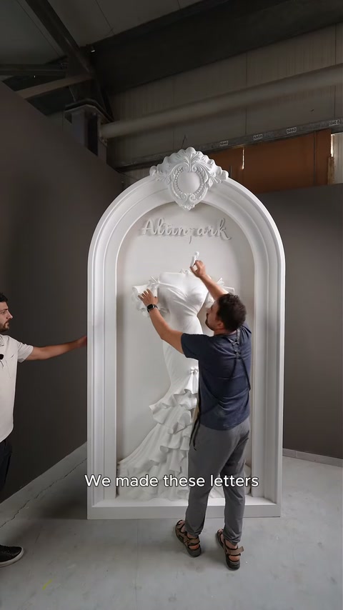 Craftsman adjusts an individual script character above the mounted gown relief.