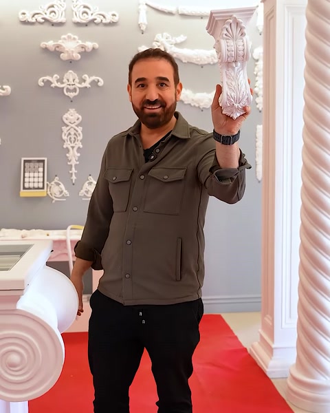 Uomo che solleva un grande capitello decorativo per mostrare la sua scultura dettagliata