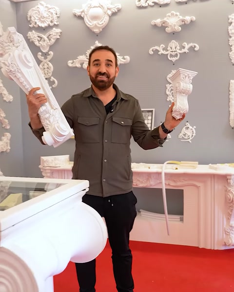 Uomo che tiene un grande capitello bianco vicino a un'esposizione di pannelli murali