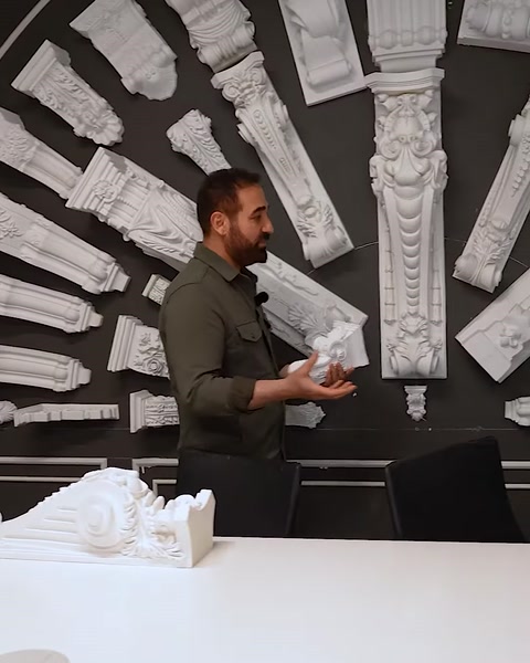 Uomo che tiene un piccolo capitello davanti a un muro di esposizione di grandi capitelli
