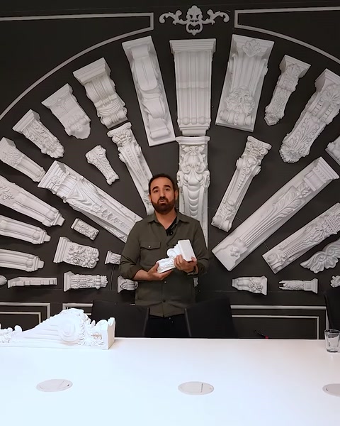 Uomo che tiene un capitello decorativo davanti a uno sfondo di muro di colonne