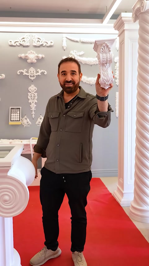 Uomo che solleva un grande capitello decorativo per mostrare la sua scultura dettagliata