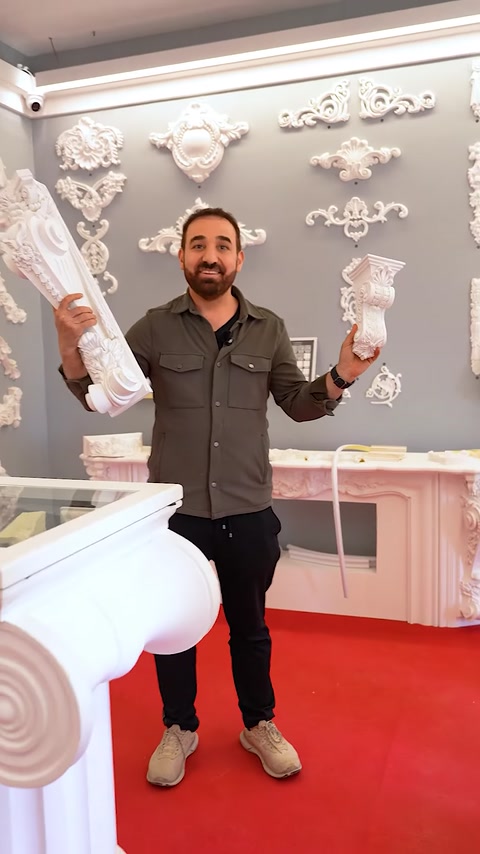 Uomo che tiene un grande capitello bianco vicino a un'esposizione di pannelli murali