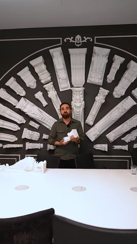Uomo che tiene un capitello decorativo davanti a uno sfondo di muro di colonne