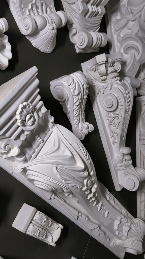 Ornate carved corbels and wall brackets mounted on dark showroom wall