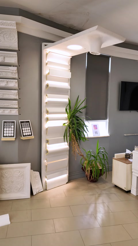 Layered stepped cornice archway framing a lit showroom doorway with plants