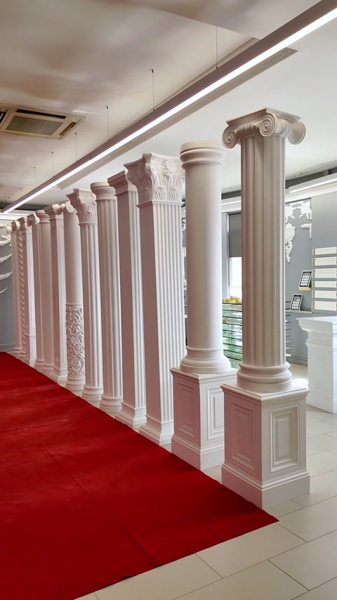 Row of fluted showroom columns lining a red carpet hallway