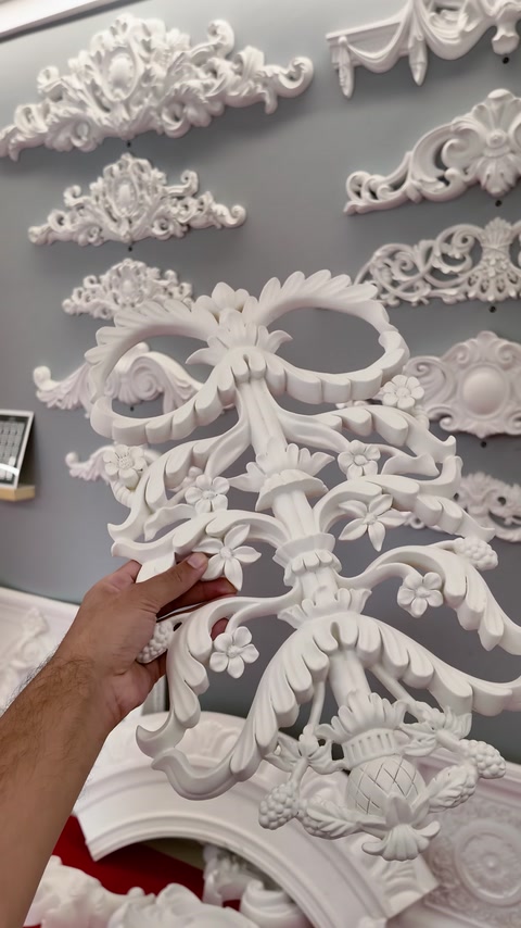 Hand touching an ornate carved wall applique panel in showroom