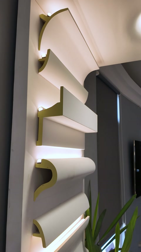 Illuminated moulding cross-sections line a dark showroom display wall.