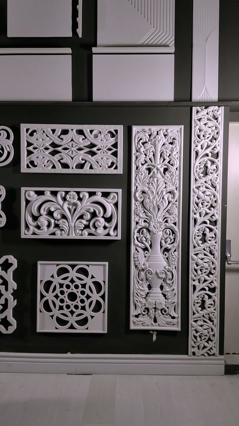 Geometric and botanical relief panels fill a black display wall.