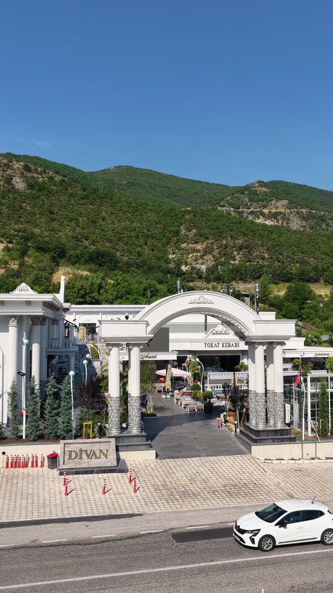 Dekoratif kemerli giriş, sütunlar ve cephe düzeniyle uzaktan görülüyor
