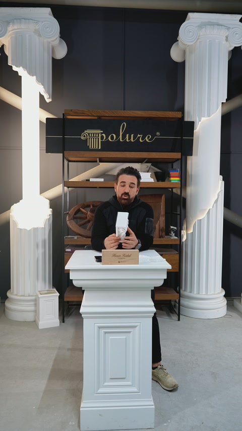 Il presentatore illustra un elemento decorativo in poliuretano espanso su un supporto espositivo in showroom