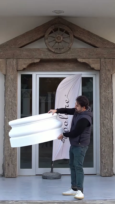 Un artigiano trasporta la base inferiore della colonna in poliuretano bianco all'esterno