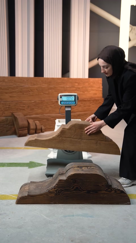 Un elemento curvo di staffa effetto legno viene posizionato per la pesatura.