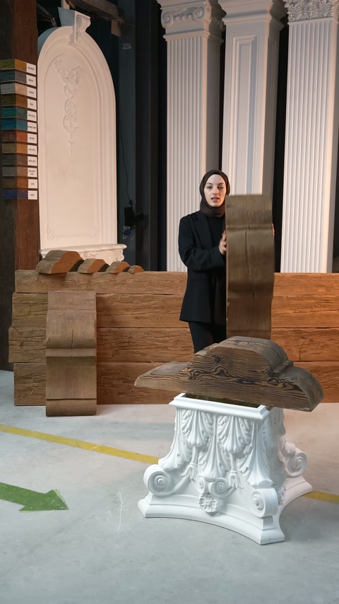L'operatore tiene verticale una lunga cornice curva davanti agli esempi di colonne decorative.