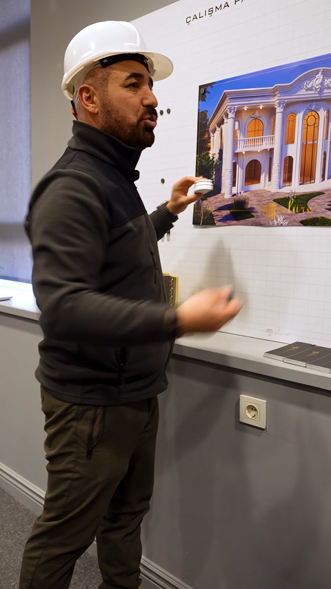 Uno specialista illustra il piccolo elemento decorativo in scala accanto al progetto di facciata.