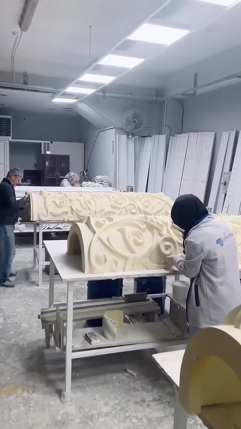 A craftsman performing final finishing work on the patterned column base surface