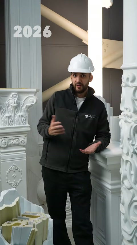 Un presentatore con berretto bianco spiega i prodotti tra colonne decorative in poliuretano