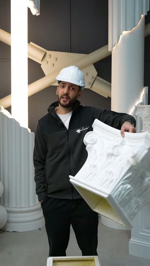 Il maestro artigiano solleva un grande capitello decorativo per esaminarne la struttura