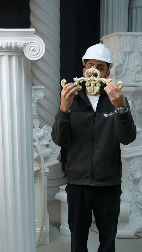 Il presentatore mostra un piccolo motivo decorativo ricurvo con entrambe le mani
