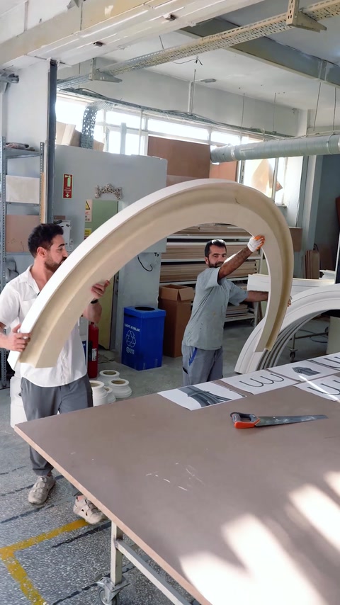 Atölyede geniş beyaz kemer modülü iki usta tarafından taşınıyor