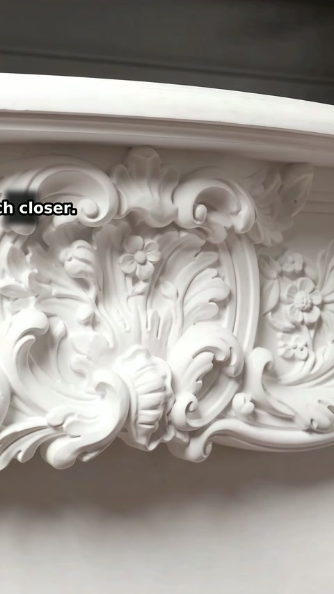 Deeply molded floral details fill the white mantel's central crest.
