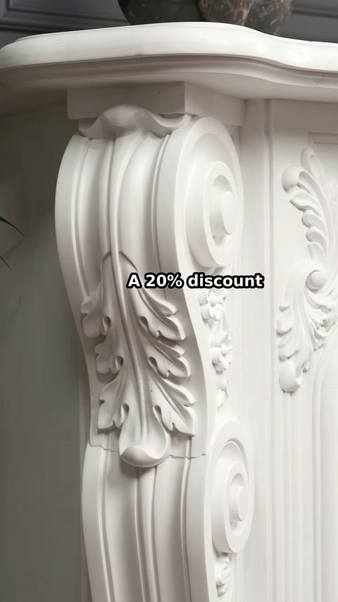The white fireplace column features sweeping curves and recessed leaf details.