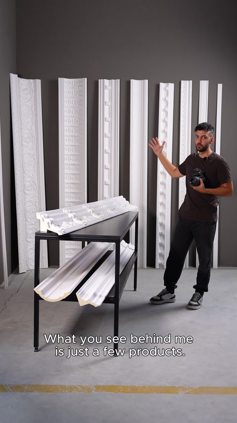 Il presentatore mostra le diverse cornici decorative disposte in laboratorio e l'area fotografica