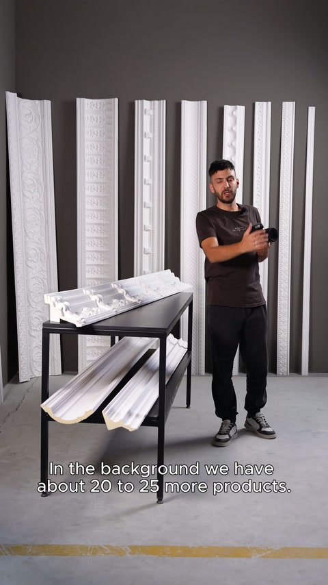 Presenter demonstrates vertical cornice samples and display table in studio
