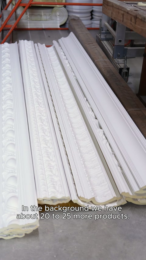 Embossed white cornices lined up parallel along wooden workbench
