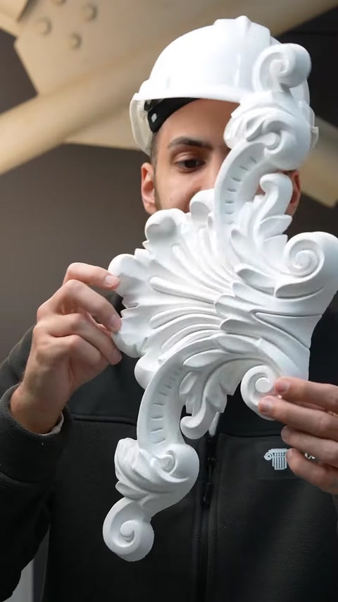 Close-up hands holding detailed white polyurethane acanthus scroll
